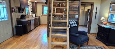 Un interior rústico con una escalera de madera, una cocina con electrodomésticos modernos y una zona de estar acogedora.