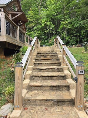 A wooden staircase with stone steps leading to a building with a balcony. - Cozy Cabin w/Loft Bedroom * Firepit * Creek Access (Dahlonega)