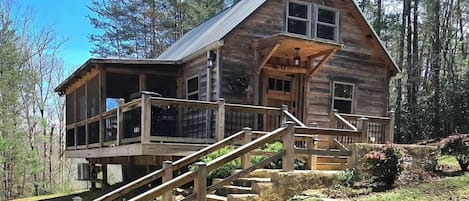 Una cabaña de madera con un porche y una escalera que lleva a ella.