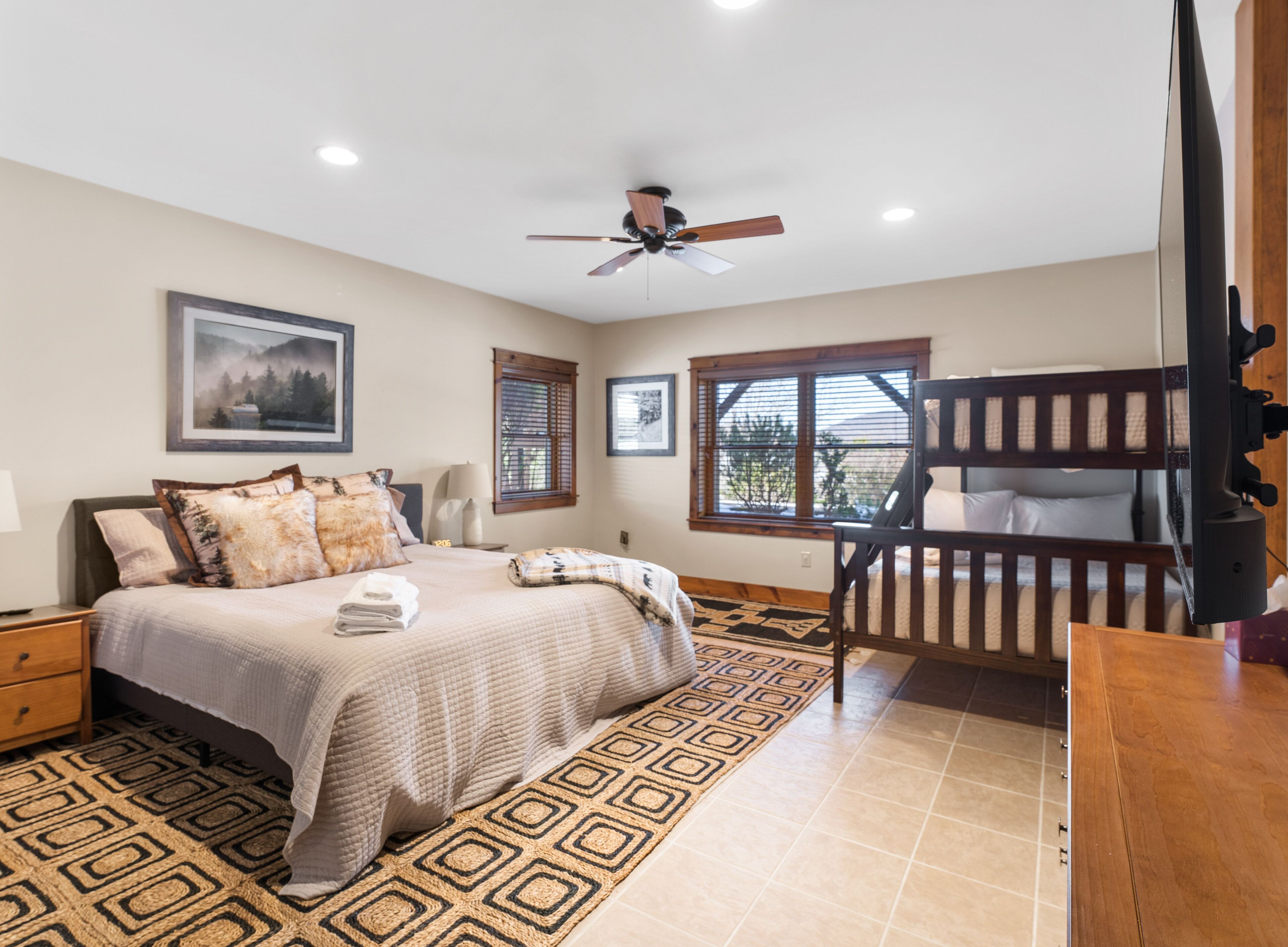 A bedroom with a bed, a ceiling fan, a window, and a bunk bed.