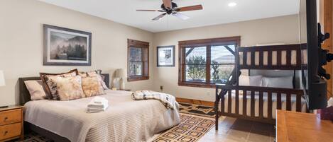 A bedroom with a bed, a ceiling fan, a window, and a bunk bed.