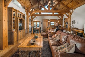 A spacious living area with wooden beams, a leather sofa, and a dining table.