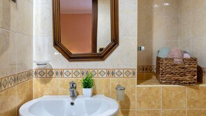 A bathroom with a white sink, a mirror, a potted plant, a wicker basket with towels, and a soap dispenser. - Bed and Breakfast 'Tripla' with Mountain View, Private Garden and Air Conditioning (Giave)