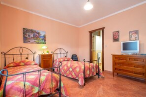A bedroom with two metal beds, a wooden dresser, a television, and a painting on the wall. - Bed and Breakfast 'Tripla' with Mountain View, Private Garden and Air Conditioning (Giave)