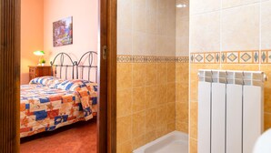 A bedroom with a bed, a nightstand, a lamp, and a bathroom with a shower and a radiator. - Bed and Breakfast 'Tripla' with Mountain View, Private Garden and Air Conditioning (Giave)