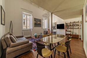 Un salon moderne comprenant un canapé, une table à manger, des chaises, un téléviseur et une bibliothèque.
