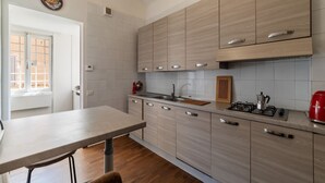 A modern kitchen with light wood cabinets, a stainless steel sink, and a gas stove.