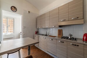 A modern kitchen with light wood cabinets, a stainless steel sink, and a gas stove.