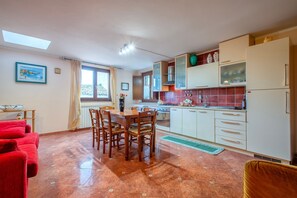 Una cocina con una mesa de comedor, sillas y un sofá rojo.