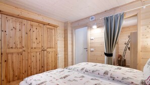 Ein Zimmer mit Holzwänden, einem Bett, einem Kleiderschrank und einer Tür zu einem Badezimmer.