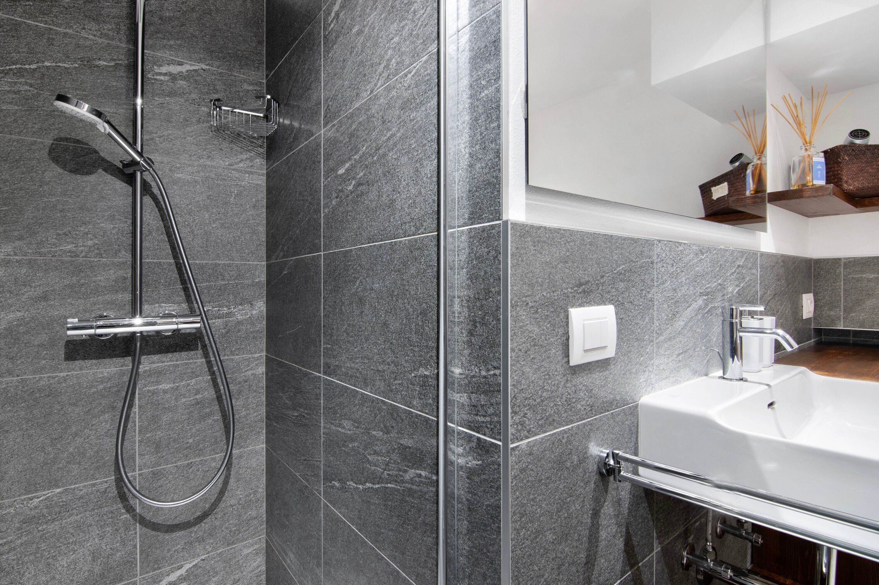 Un baño moderno con ducha, lavamanos y espejo.