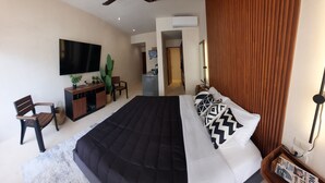 A bedroom with a large bed, a ceiling fan, a TV mounted on the wall, a wooden cabinet, and a desk with a chair. - Beautiful & Fully Equipped Condo Studio Strategically located (Tulum)