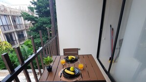 A balcony with a table set for two, featuring a potted plant, a banana, and a glass of orange juice. - Beautiful & Fully Equipped Condo Studio Strategically located (Tulum)