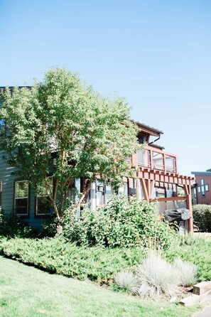 Un edificio de varios pisos con una combinación de elementos arquitectónicos modernos y tradicionales, rodeado de abundante vegetación.