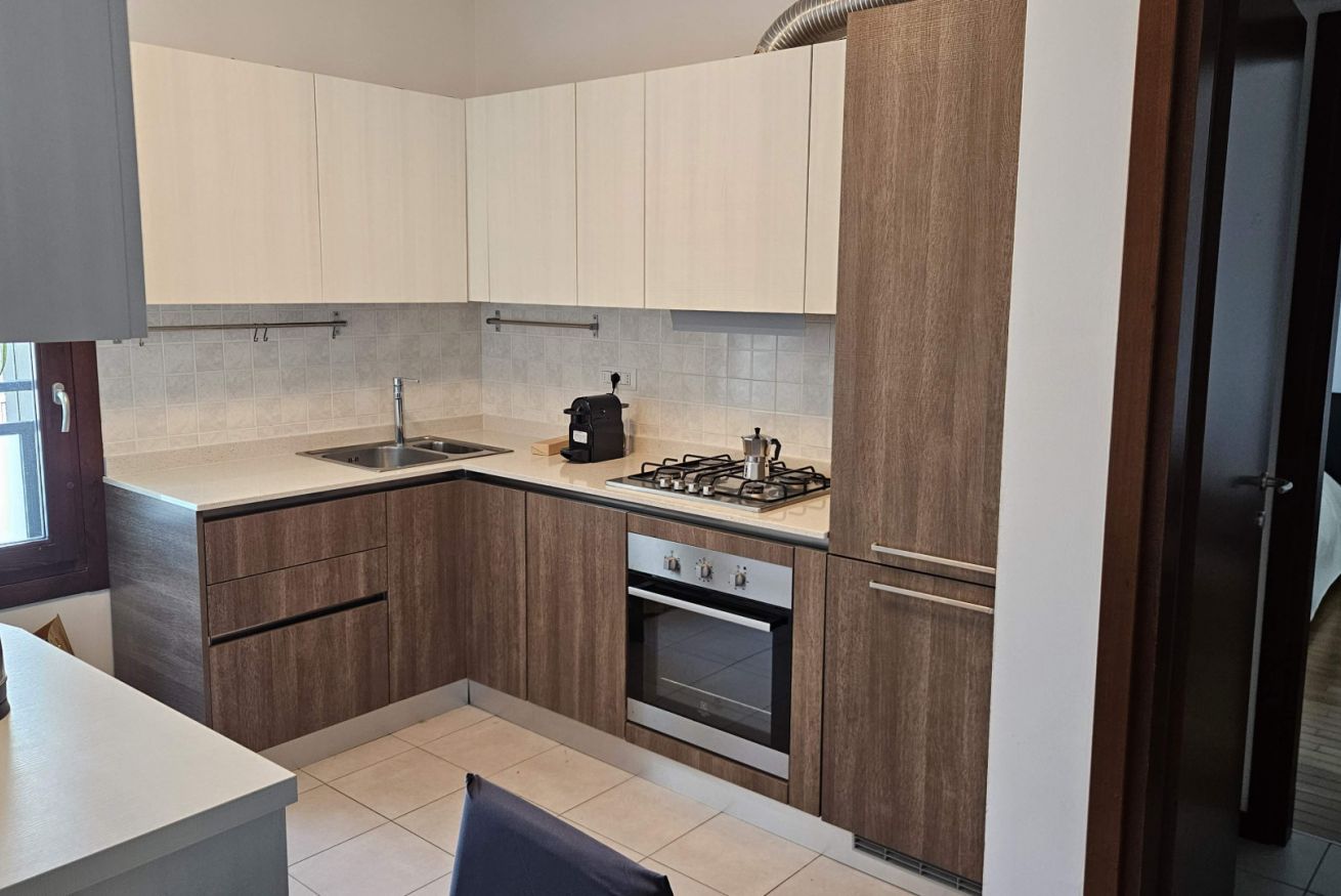 A kitchen with wooden cabinets, a gas stove, a sink, and a refrigerator.