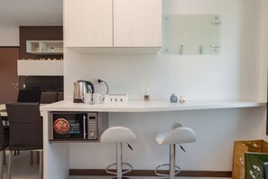 A modern kitchen with a coffee machine, tea station, and bar stools. - Check in information:You won’t need to meet anyone to access the apartment. Before arrival, you will receive a link to access the Guest Portal, where you can complete the self check-in directly from your phone by entering the ID details of all guests a (Milan)