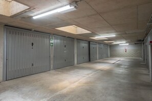 A long corridor with grey lockers, fluorescent lighting, and a fire extinguisher on the wall. - Check in information:You won’t need to meet anyone to access the apartment. Before arrival, you will receive a link to access the Guest Portal, where you can complete the self check-in directly from your phone by entering the ID details of all guests a (Milan)