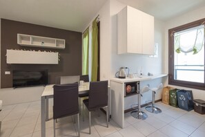 Una cocina moderna con comedor, televisor y ventana con cortinas.