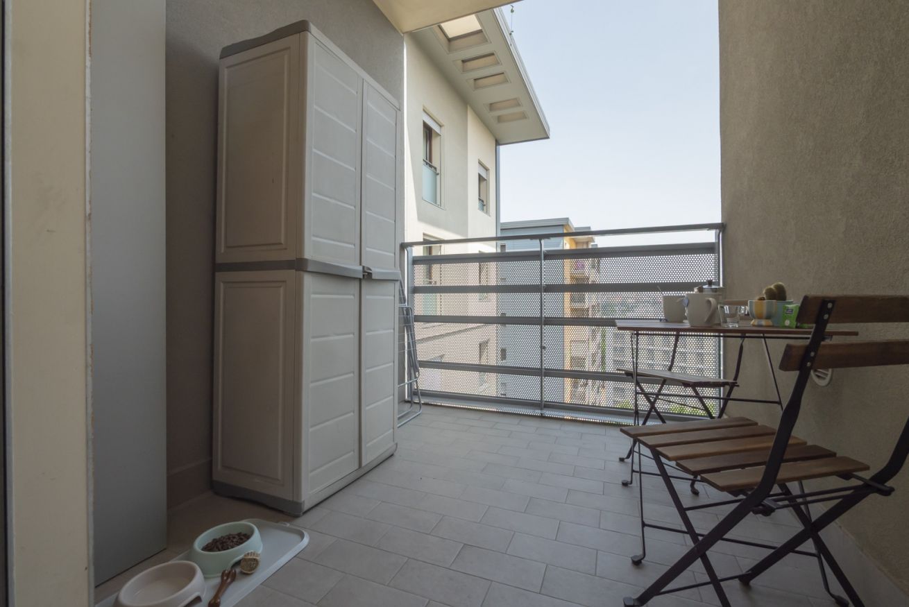 En balkon med gelænder, et lille bord og en klapstol.