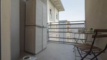 En balkon med gelænder, et lille bord og en klapstol.