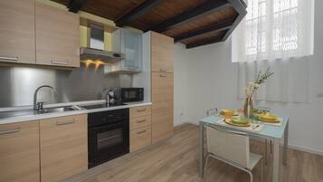 Una cucina moderna con mobili in legno, elettrodomestici in acciaio inox e un'area pranzo con tavolo e sedie.