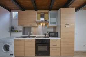 Eine kleine Küche mit Waschmaschine, Backofen, Mikrowelle und Holzschränken.