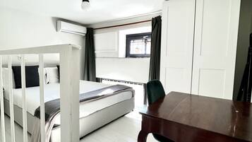 A bedroom with a bed, a wooden table, a chair, a wardrobe, and a window with curtains.