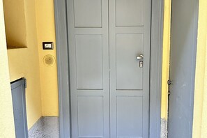 Une porte grise fermée, avec une serrure et une petite pancarte fixée au mur, sur le côté gauche.