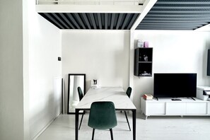 A modern room with a white dining table, a green chair, a flat-screen TV, and a white cabinet.