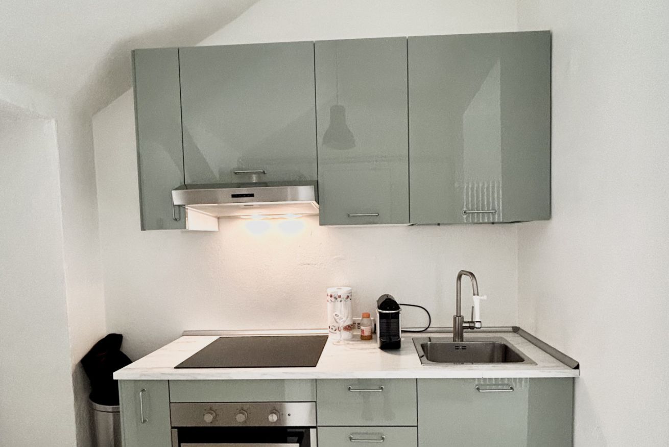 A kitchen with a stove, sink, and cabinets.