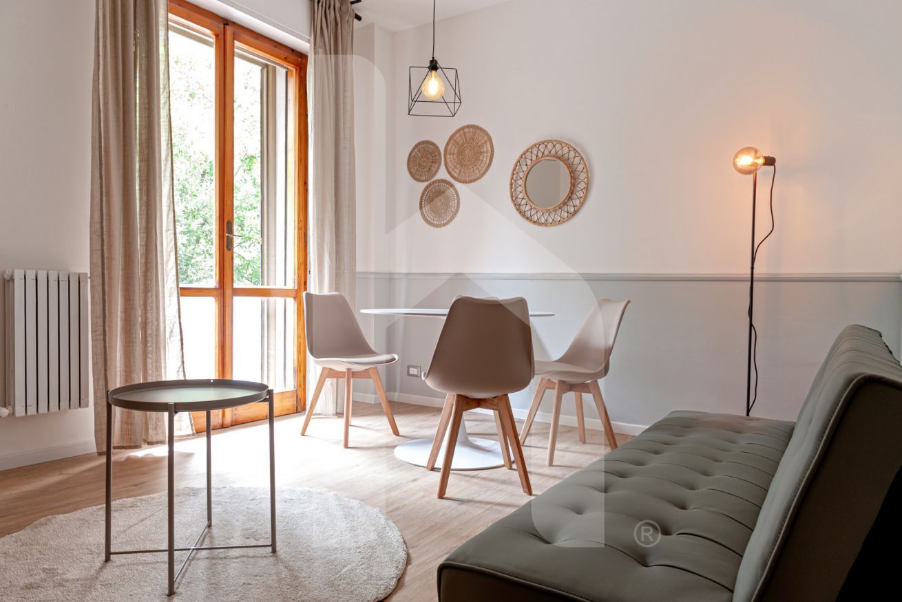 Una sala de estar moderna con un sofá, sillas, una mesa redonda y una lámpara de pie.