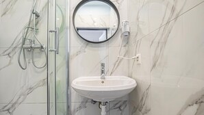 A bathroom with a glass shower enclosure, a white sink, and a round mirror. - Bright & Modern Room in Vienna’s Meidling District (Vienna)