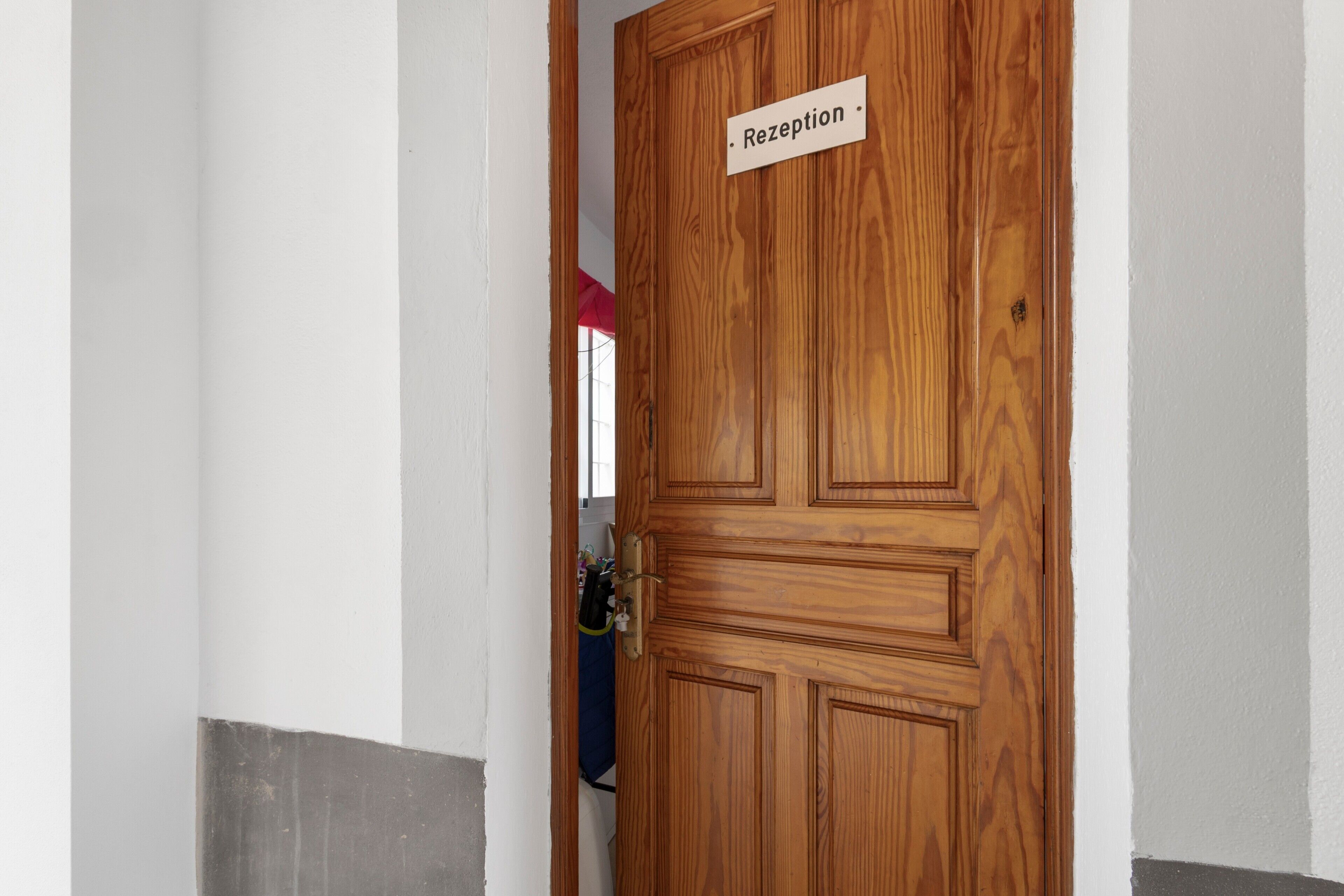 Puerta de madera con la etiqueta 'Reception', un ojo de cerradura y un tirador de metal.
