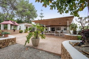A covered outdoor seating area with tables and chairs, surrounded by potted plants and a stone wall. - Room 'Doble - 2' with Mountain View, Wi-Fi and Air Conditioning (Santa Eulària des Riu)