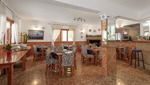 Um restaurante com várias mesas e cadeiras, um bar e uma lareira.
