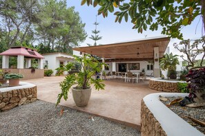 A covered outdoor seating area with tables and chairs, surrounded by potted plants and a stone wall. - Room 'Doble - 5' with Mountain View, Wi-Fi and Air Conditioning (Santa Eulària des Riu)