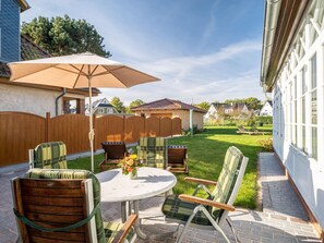 Un patio con una mesa redonda y sillas, una sombrilla y una valla de madera.