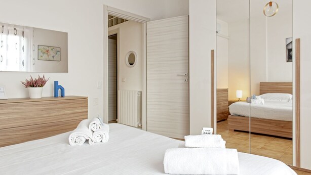 A hotel room with a bed, a dresser, a mirror, a radiator, and a small potted plant. - Homiday - Hospital/Airport- A/C and Free Parking (Pisa)