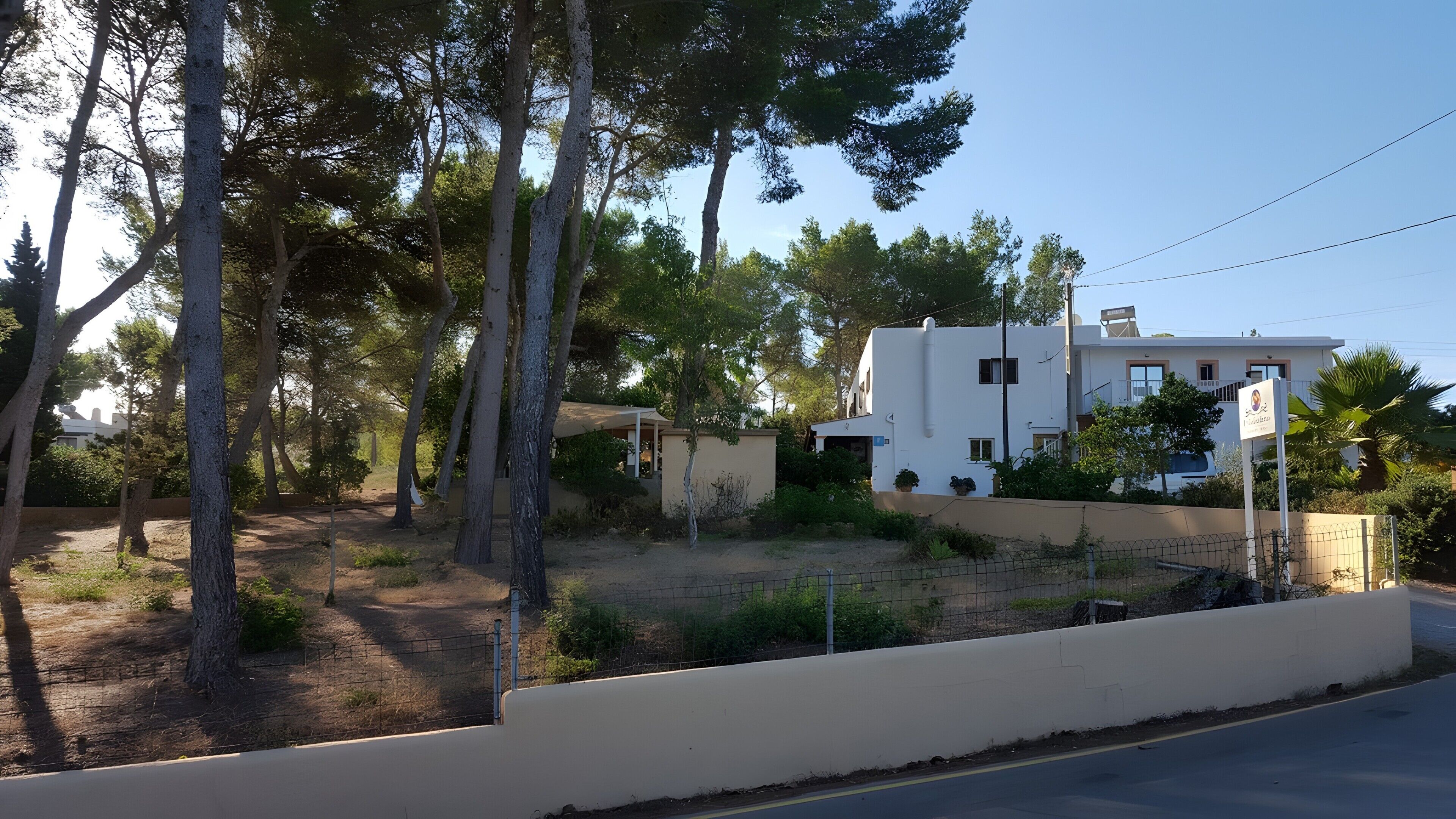 Un barrio residencial con un edificio blanco, árboles y una calle.