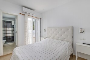 A bedroom with a bed, a bedside table, an air conditioning unit, and a bathroom visible through an open door. - Room 'Doble - 4' with Mountain View, Wi-Fi and Air Conditioning (Santa Eulària des Riu)