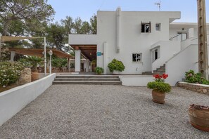 A white building with a covered entrance, steps leading to a door, and potted plants. - Room 'Doble - 4' with Mountain View, Wi-Fi and Air Conditioning (Santa Eulària des Riu)