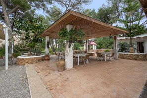 An outdoor patio area with a wooden pergola, stone seating, and potted plants. - Room 'Doble - 4' with Mountain View, Wi-Fi and Air Conditioning (Santa Eulària des Riu)