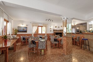 A restaurant with multiple tables and chairs, a bar area, and a fireplace. - Room 'Doble - 4' with Mountain View, Wi-Fi and Air Conditioning (Santa Eulària des Riu)
