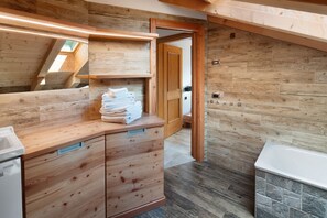 Une salle de bain moderne avec des meubles en bois, un mur d’accent en pierre et une lucarne.