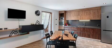 A modern kitchen with wooden cabinets, a built-in oven, and a stainless steel refrigerator.