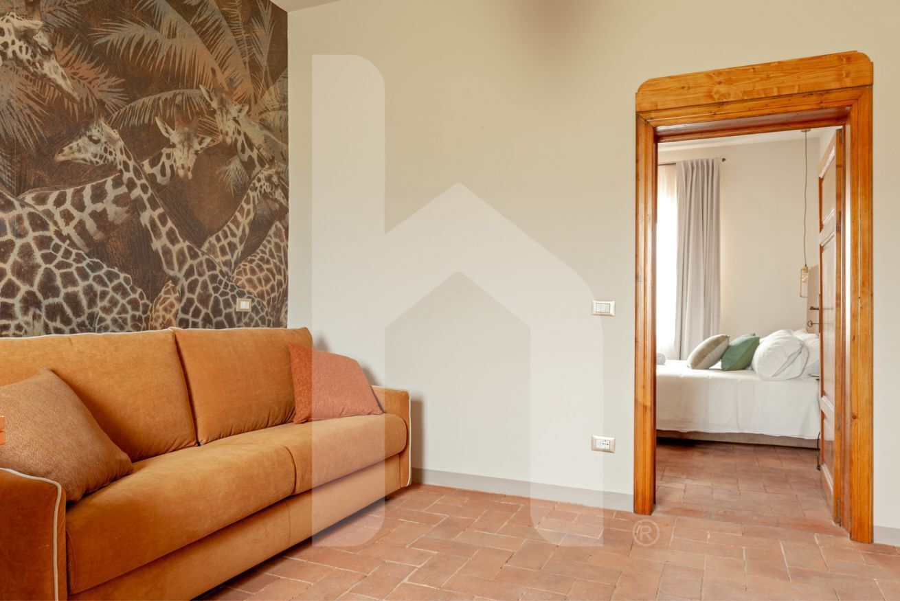 A room with a sofa, a bed, and a mural of giraffes on the wall.