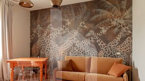 A room with a giraffe-themed mural, a wooden table with clear chairs, and a brown sofa.