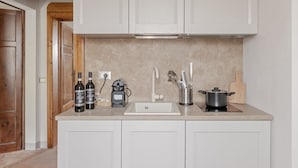 A small kitchen with a sink, two bottles of wine, a kettle, and a pot on the counter. - RINOCERONTE: Relax and enjoy this simple yet elegant apartment, equipped with all the comforts: PRIVATE parking, FULL HD TV, AIR CONDITIONING, and a fully equipped bathroom with a walk-in shower. All of this just 10 minutes from Pisa and 25 minutes from  (San Giuliano Terme)