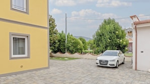 A white Audi parked in a driveway with a yellow building on the left and a white building on the right. - RINOCERONTE: Relax and enjoy this simple yet elegant apartment, equipped with all the comforts: PRIVATE parking, FULL HD TV, AIR CONDITIONING, and a fully equipped bathroom with a walk-in shower. All of this just 10 minutes from Pisa and 25 minutes from  (San Giuliano Terme)