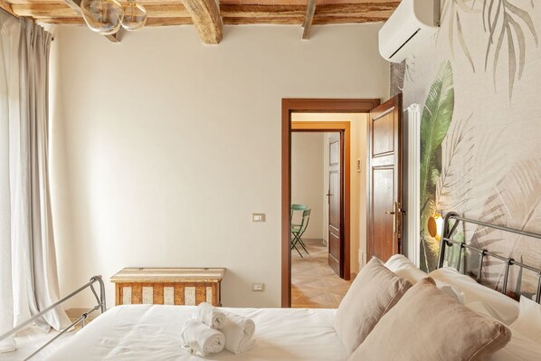 A bedroom with a bed, a wooden bench, a chair, and a door leading to a bathroom.
